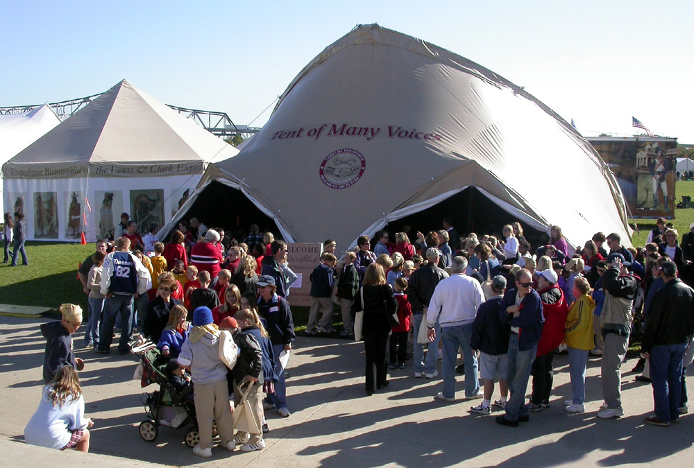 A group gathers into a large display tent